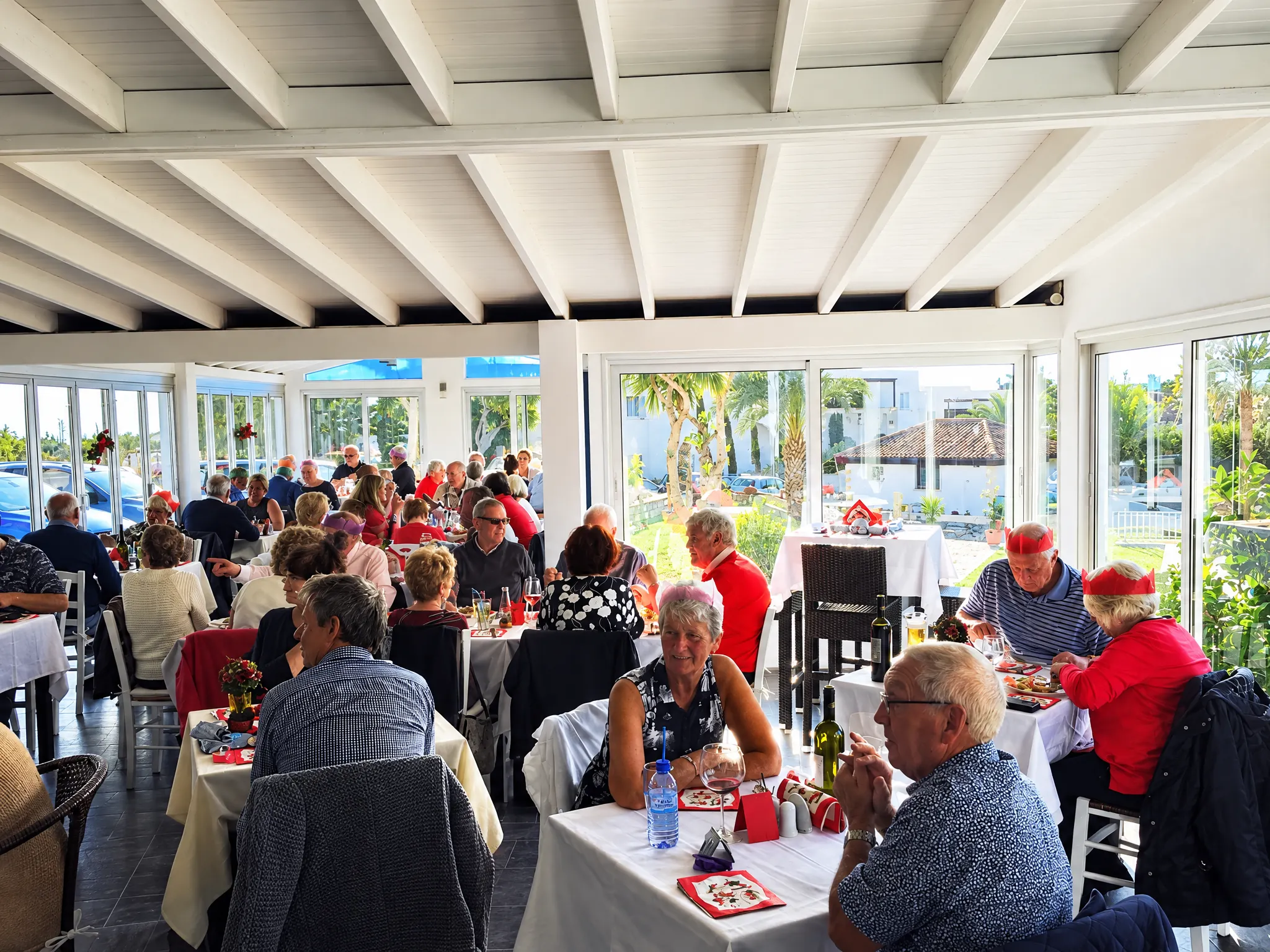 A full dining room at Haris, guests at long tables by the big windows